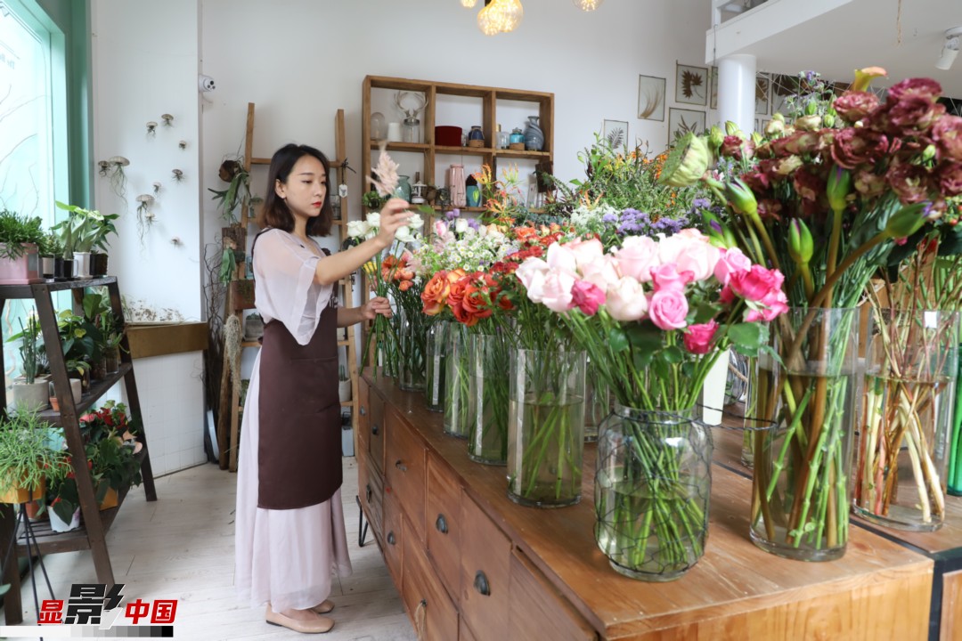 王黎媛是一名河南姑娘，在昆明念完大學后，就再也舍不下春城的藍天陽光、青山碧水，更舍不下這里的四時繁花，于是就干脆留了下來，成了一名媒體人。2017年的時候又毅然辭去工作，創(chuàng)業(yè)開起了花店，成了都市里的一名“花房姑娘”。圖為王黎媛在自己的花店中整理鮮花。新華網 周亞平/攝 念新洪/文